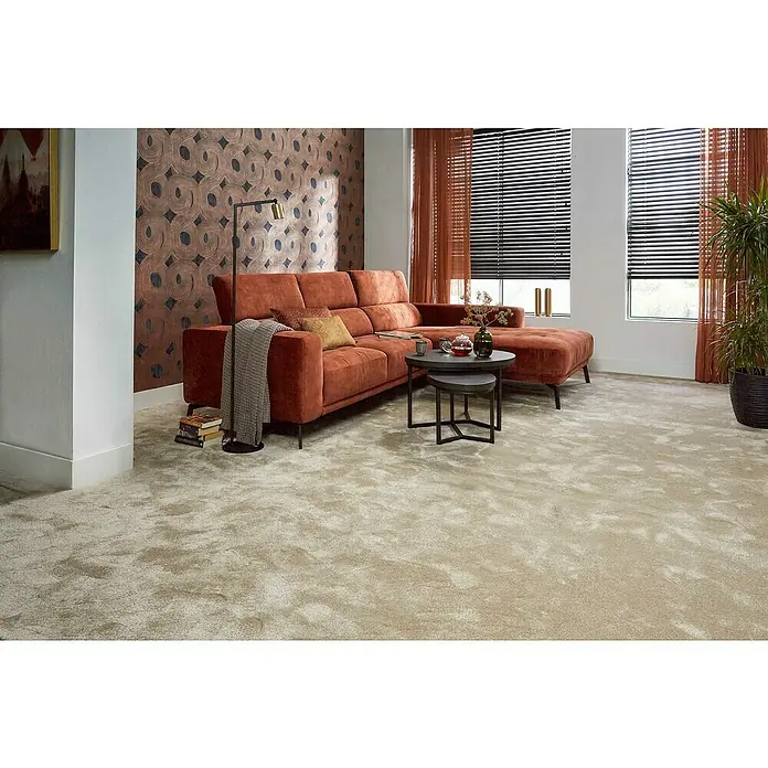 Teppichfliese Amazing - Hochflor, 100 % Polyester, Hellbraun - Wohnzimmer mit einem modularen, orangefarbenen Ecksofa, das mit Kissen und einer Decke ausgestattet ist, vor einer gemusterten Wand.