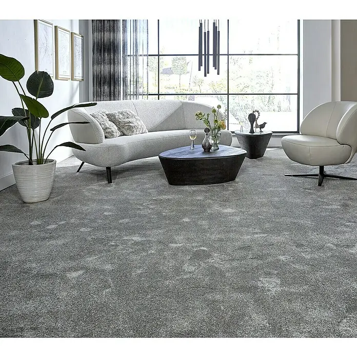 Teppichfliese Amazing - Hochflor, 100 % Polyester, Grau - Ein modernes Wohnzimmer mit einem luxuriösen grauen Teppich, einem eleganten Sofa und einem stilvollen Sessel, die eine einladende Atmosphäre schaffen.