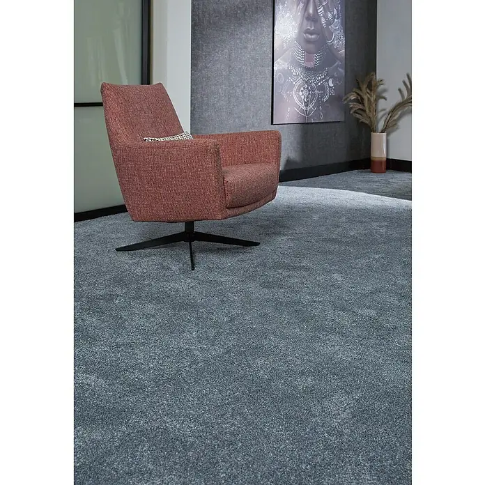 Teppichfliese Amazing - Hochflor, 100 % Polyester, Dunkelgrau - Nahaufnahme eines modernen Sessels in einem eleganten Raum mit einem grauen Teppich, der für Komfort und Stil sorgt.