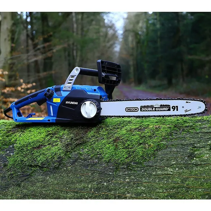 Hyundai Elektro-Kettensäge CS2416E - 2.400 W, Schwertlänge: 400 mm - Nahaufnahme einer blauen Hyundai-Kettensäge mit einer Oregon Double Guard 91-Kette auf einem Baumstamm im Wald.