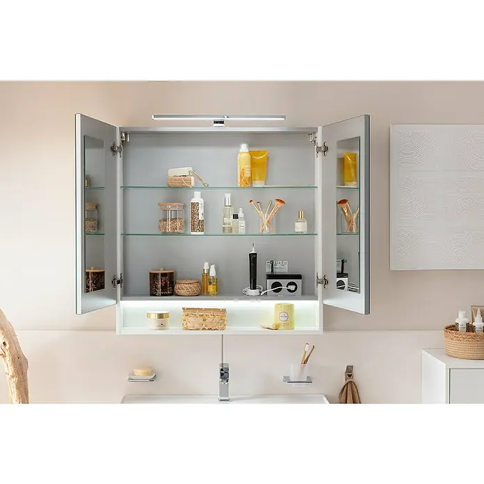 Camargue Curve Badmöbel-Set - Gesamtbreite Badmöbel: 80 cm, Matt, Weiß, 3 -tlg. - Ein offener Badezimmerschrank mit Glasböden und einer Vielzahl von Badartikeln, beleuchtet durch eine LED-Leiste, präsentiert ein modernes Design.