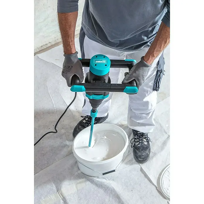 Collomix Mixbro Rührwerk M130 - Mischvolumen: 50 l, Gangzahl: 1 Stk. - Ein Arbeiter benutzt einen Mörtelrührer MIXBRO M120, um in einem Eimer Farbe zu mischen. Perfekt für Renovierungsarbeiten.