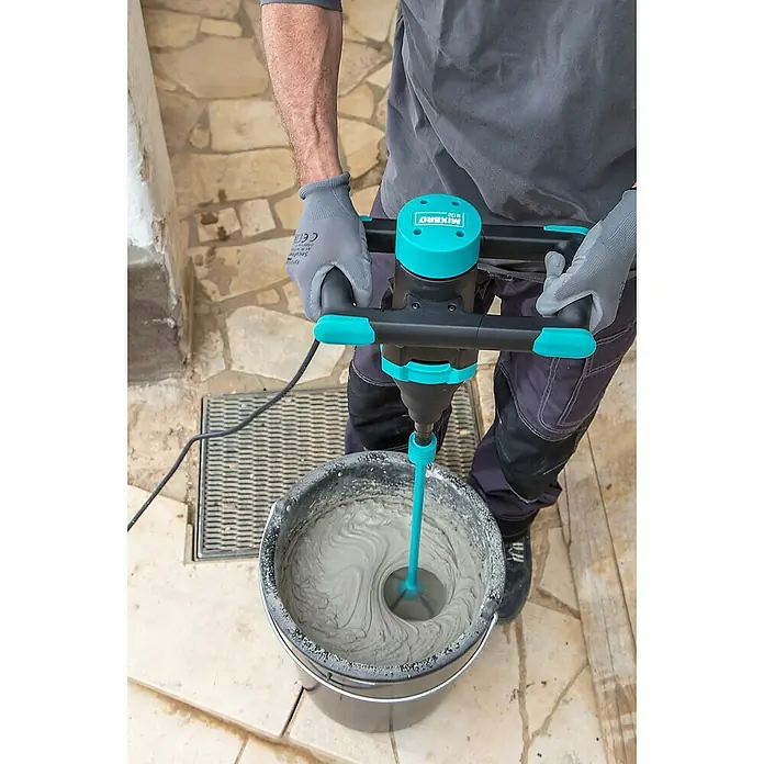 Collomix Mixbro Rührwerk M130 - Mischvolumen: 50 l, Gangzahl: 1 Stk. - Ein Mann benutzt einen MIXERÖ M130 Mörtelrührer, um Zement in einem schwarzen Eimer zu mischen. Er trägt dabei graue Arbeitshandschuhe.
