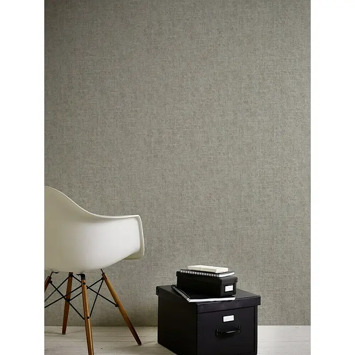 A.S. Création Greenery Vliestapete Borneo - Braun/Grau, Uni, 10,05 x 0,53 m - Stilvolles Interieur mit einem modernen Stuhl und Aufbewahrungsboxen vor einer dezenten, strukturierten Wand.