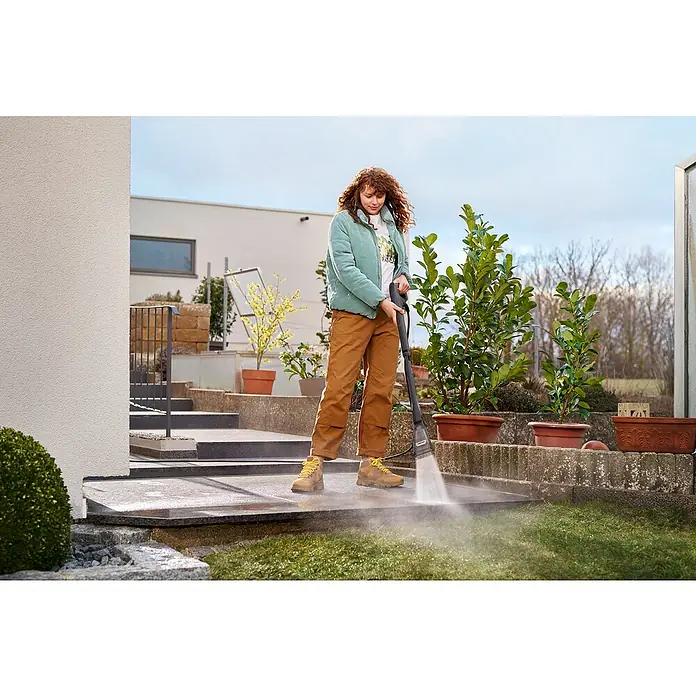 Kärcher Strahlrohr eco!Booster 130 - Passend für: Kärcher Hochdruckreiniger der Klassen K4, 615 x 108 x 51 mm - Frau reinigt die Terrasse mit einem Kärcher Hochdruckreiniger, um Schmutz zu entfernen und die Oberfläche aufzufrischen.