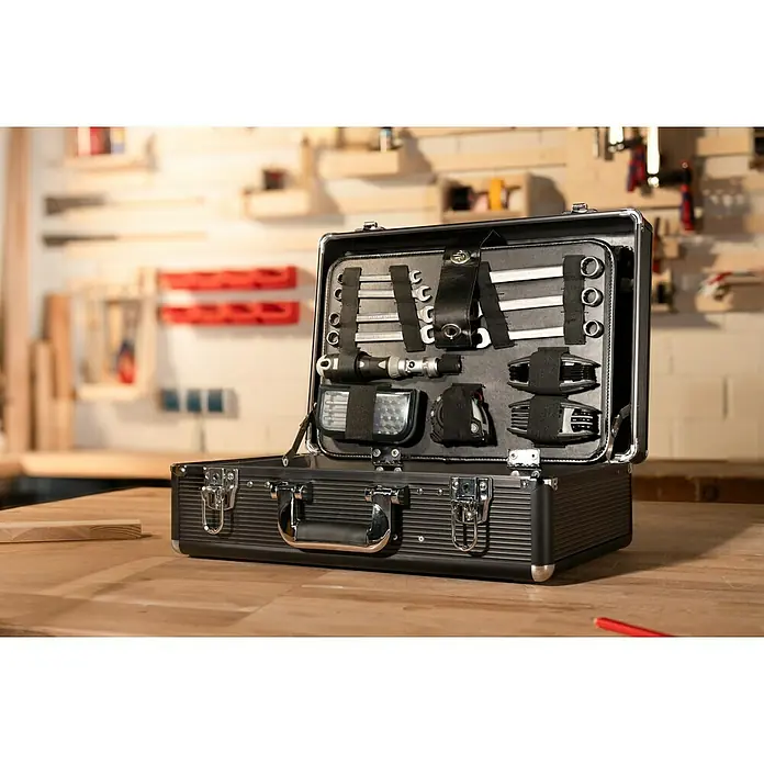 Alpha Tools Werkzeugkoffer - L x B x H: 450 x 305 x 167 mm, Aluminium, 119 -tlg. - Ein offener Werkzeugkoffer auf einer Holzoberfläche. Die Werkzeuge sind ordentlich in dem Koffer verstaut. Werkstatt im Hintergrund.