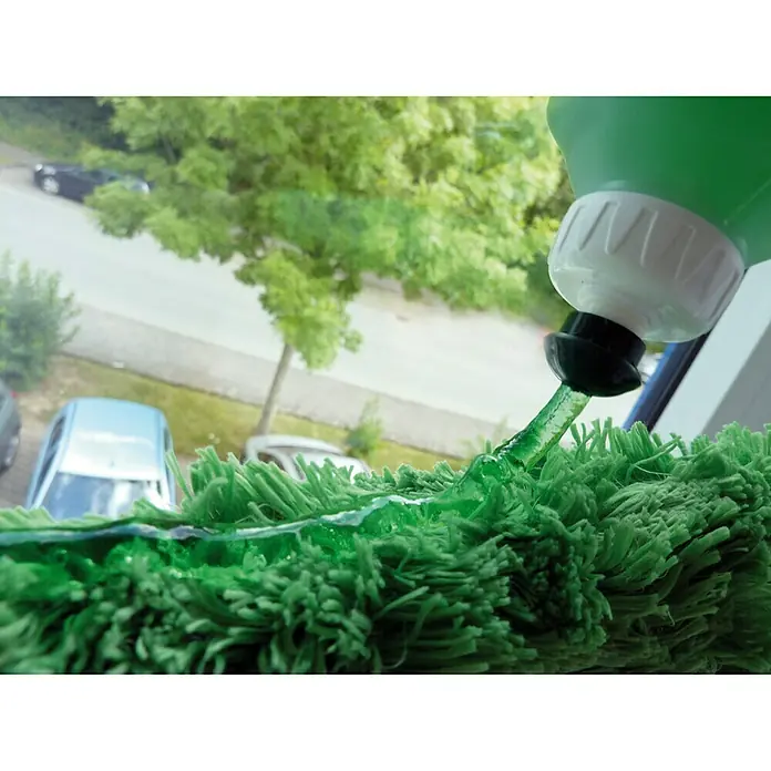 Unger Gel-Glasreiniger - 500 ml - Detailaufnahme eines Fensterreinigungsgeräts, das grüne Flüssigkeit auf ein grünes Mikrofaserpad sprüht, mit Außenansicht im Hintergrund.