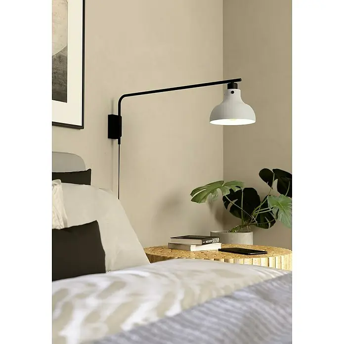 Eglo Matlock Aplique de pared - 40 W, L x Al: 20 x 25 cm, Gris, E27 - Una elegante y moderna lámpara de pared en blanco y negro ilumina una mesita de noche con libros y una planta en el dormitorio.
