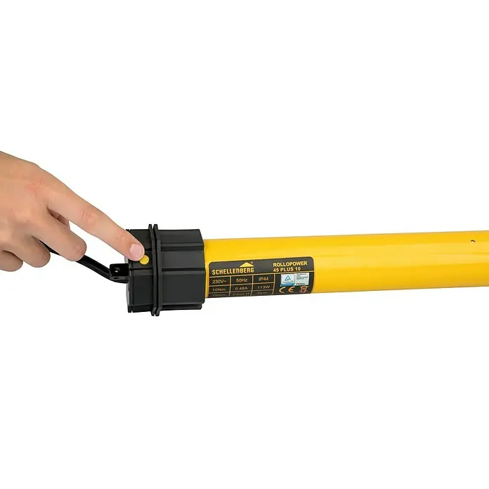 Schellenberg Motor tubular Maxi Plus - Superficie de persiana enrollable máx.: 4,2 m² para persianas de plástico, Longitud de instalación: 555 mm, Fuerza de tracción: 20 kg - Schellenberg RolloPower 45 Plus 10 con carcasa amarilla. Una mano presiona un botón para operar el motor de la persiana enrollable.