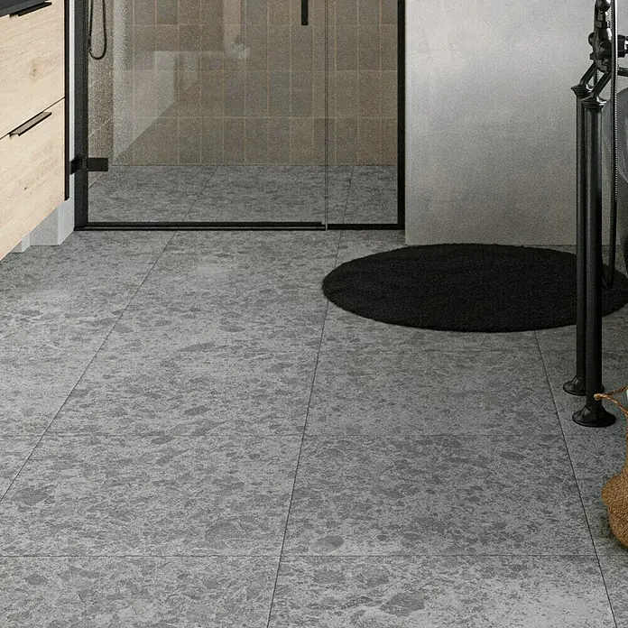 Feinsteinzeugfliese Hannover Steel - 60 x 60 cm, Grau, Matt - Graue Bodenfliesen im Badezimmer. Die Fliesen haben ein unregelmäßiges Muster und eine matte Oberfläche, die dem Raum ein modernes Aussehen verleiht.