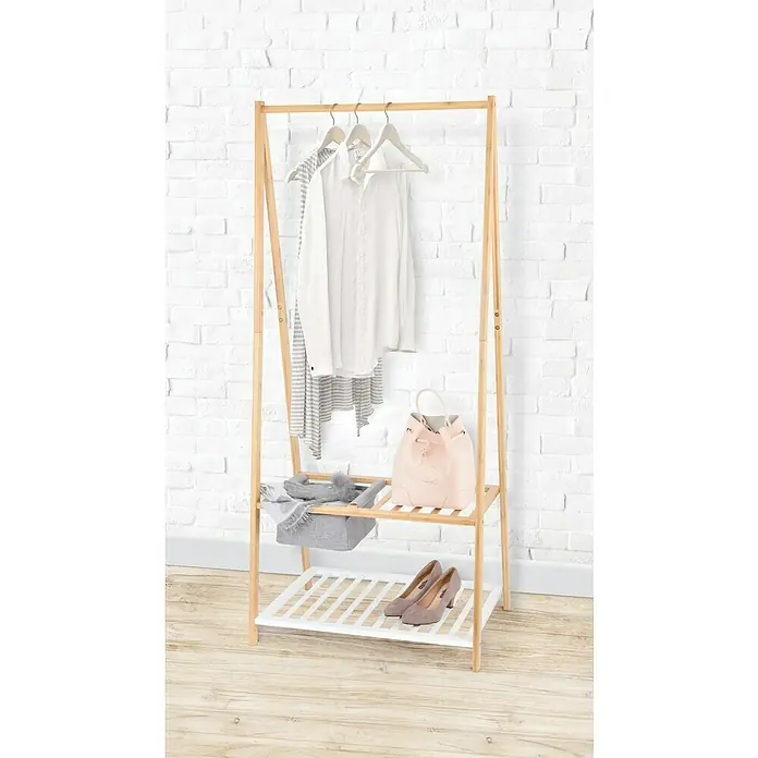 Perchero de pie con cesto de almacenaje - L x An x Al: 45 x 70 x 160 cm, Bambú/blanco - Un moderno perchero de madera con detalles blancos que incluye ropa, zapatos y accesorios, contra una pared de ladrillos blanca.