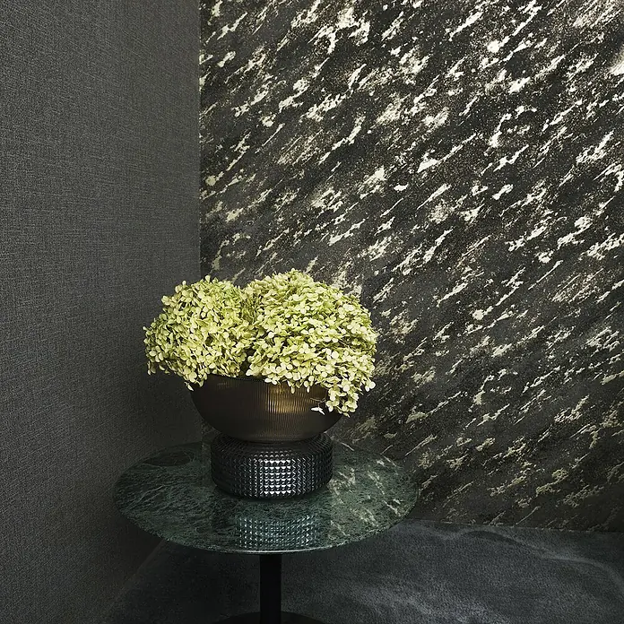 Marburg Eclectic Vliestapete Marmoroptik - Braun-Gold, Steinoptik, 10,05 x 0,7 m - Dekoratives Interieur mit einer grünen Hortensie in einer dunklen Vase auf einem grünen Marmortisch vor einer strukturierten Wand.