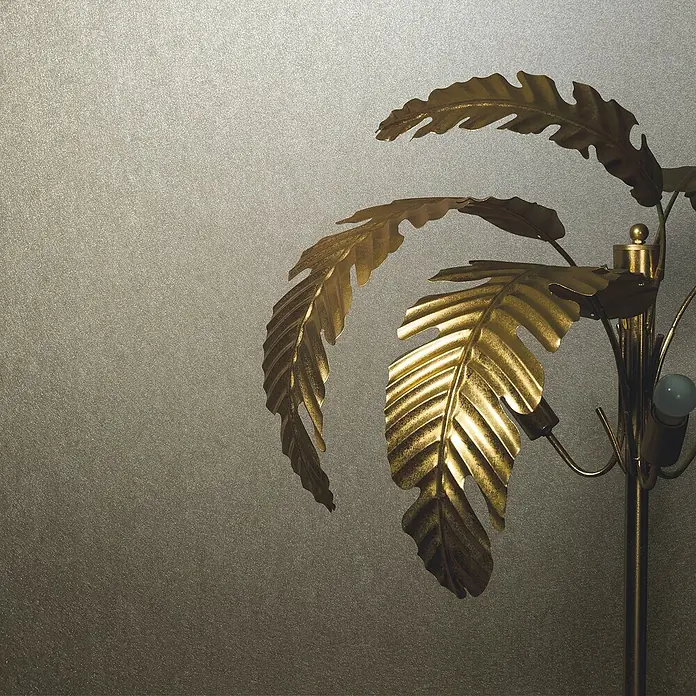 Marburg Eclectic Vliestapete - Graubeige, Metalloptik, 10,05 x 0,7 m - Nahaufnahme einer goldenen Stehlampe in Palmenform mit kunstvollen Blättern und einem dekorativen Design vor strukturiertem Hintergrund.
