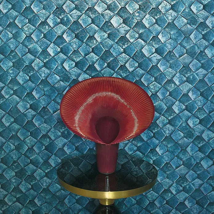 Marburg Eclectic Vliestapete Pentagonmuster - Blau, Grafisch, 10,05 x 0,7 m - Rote Vase auf einem eleganten Tisch, vor einem Hintergrund mit blauem Diamantenmuster, die das einzigartige Design hervorhebt.