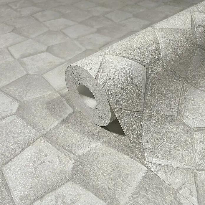 Marburg Eclectic Vliestapete Pentagonmuster - Weißbeige, Grafisch, 10,05 x 0,7 m - Nahaufnahme einer Rolle strukturierter, grauer Steinmauer-Tapete, die eine realistische, dreidimensionale Oberfläche zeigt.