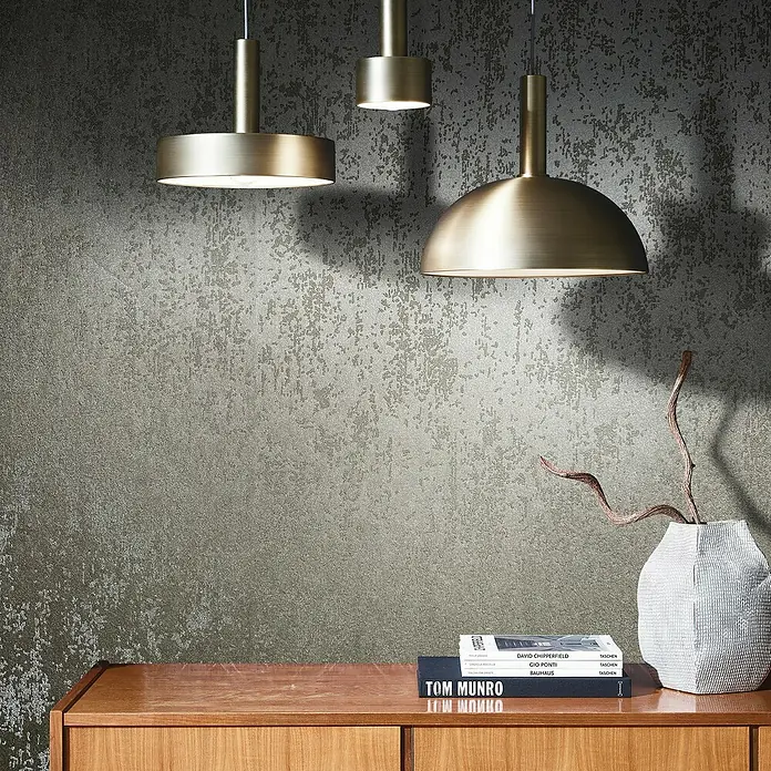 Marburg Eclectic Vliestapete Glasperlenstruktur - Braun, Metalloptik, 10,05 x 0,7 m - Diese Aufnahme zeigt drei moderne goldene Pendelleuchten über einem Holzschrank, die ein stilvolles und elegantes Ambiente schaffen.