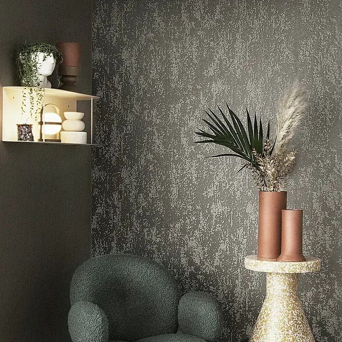 Marburg Eclectic Vliestapete Glasperlenstruktur - Braun, Metalloptik, 10,05 x 0,7 m - Dekorative Inneneinrichtung mit einem modernen Sessel, einem Beistelltisch mit Vasen und einer Wandregal-Dekoration.