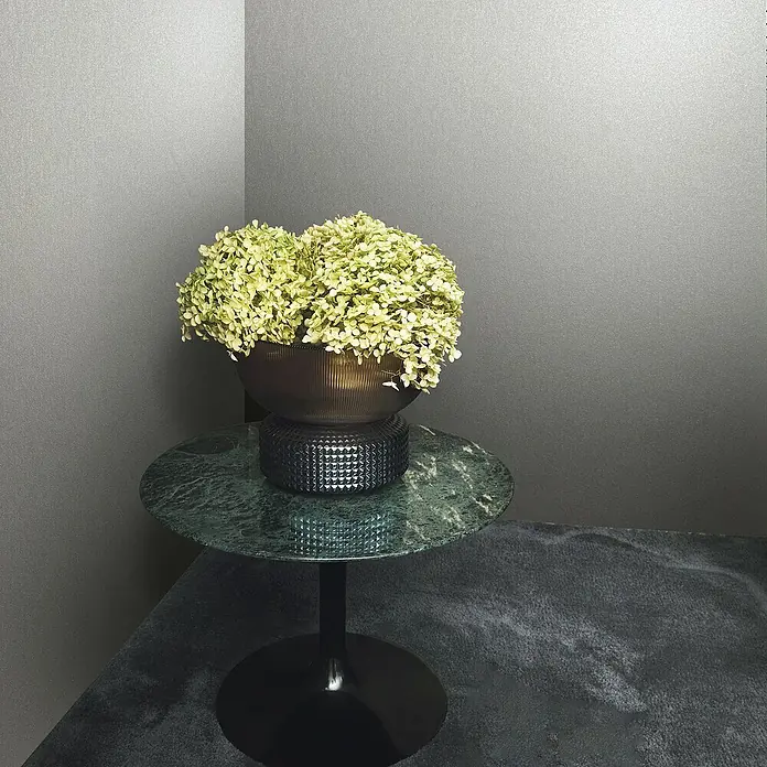 Marburg Eclectic Vliestapete Hammerschlag-Optik - Greige, Metalloptik, 10,05 x 0,7 m - Nahaufnahme eines eleganten Beistelltisches mit grüner Marmorplatte, darauf eine dekorative Blumenvase, vor einem schlichten Hintergrund.