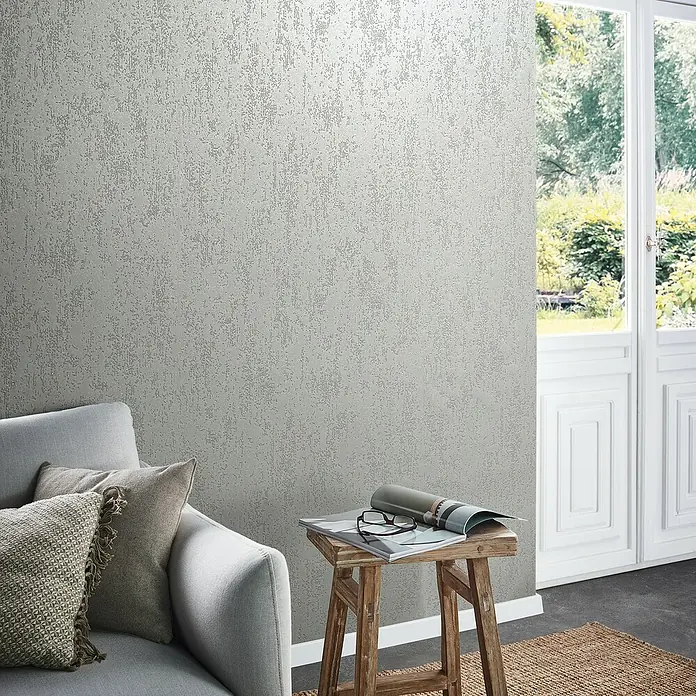 Marburg Eclectic Vliestapete Glasperlenstruktur - Lichtgrau, Metalloptik, 10,05 x 0,7 m - Nahaufnahme einer Wand mit silberner Metallic Tapete mit einer subtilen Textur für ein modernes und stilvolles Interieur.
