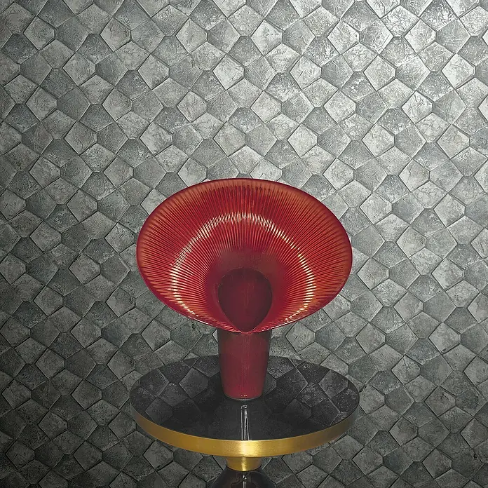 Marburg Eclectic Vliestapete Pentagonmuster - Graugold, Grafisch, 10,05 x 0,7 m - Roter Glasblumenvase auf einem schwarzen und goldenen Tisch vor einer grauen, geometrischen Hintergrundstruktur.