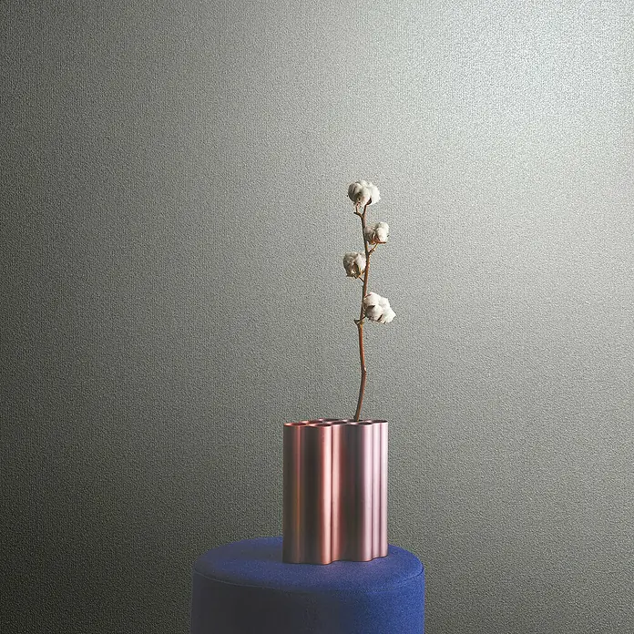 Marburg Eclectic Vliestapete - Sandbeige, Uni, 10,05 x 0,7 m - Dekorative Nahaufnahme einer eleganten Blumenvase mit zarten Baumwollblüten auf einem blauen Hocker vor einem strukturierten Hintergrund.