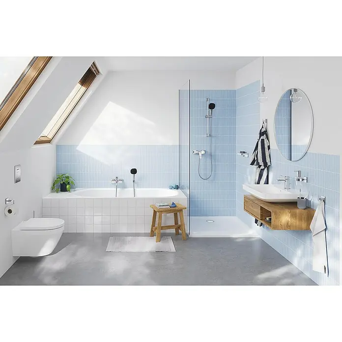 Grohe QuickFix Brausegarnitur - Lochabstand: 47 cm - 62 cm, Anzahl Strahlarten: 2 Stk. - Modernes Badezimmer mit weißen und blauen Fliesen, einer Badewanne und einem Waschtisch mit Holzunterschrank. Ein heller Raum mit Dachfenstern.