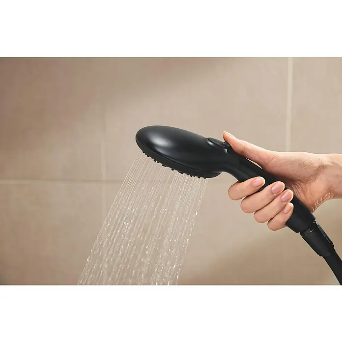 Grohe Vitalio Start Duschsystem 250 - Höhe: 101,6 cm, Anzahl Strahlarten: 2 Stk., Schwarz - Eine Hand hält einen schwarzen Duschkopf, aus dem Wasser strömt, vor einem hellen, gefliesten Hintergrund.