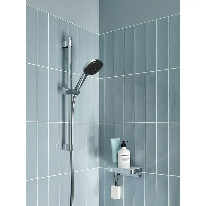 Grohe QuickFix Brausegarnitur - Lochabstand: 47 cm - 62 cm, Anzahl Strahlarten: 2 Stk. - Eine Duscharmatur mit Handbrause und einem Regal mit Shampoo und Seife an einer blau gefliesten Duschwand.