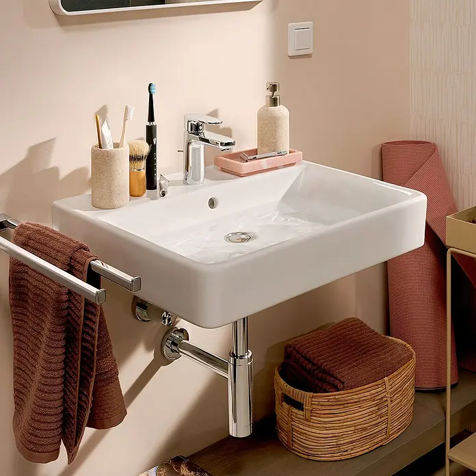 Hansgrohe Vernis Blend Waschtischarmatur 100 CoolStart - Chrom, Glänzend - Nahaufnahme eines modernen Badezimmers mit einem weißen Waschbecken, Armaturen, Handtüchern und Badutensilien für einen stilvollen Touch.