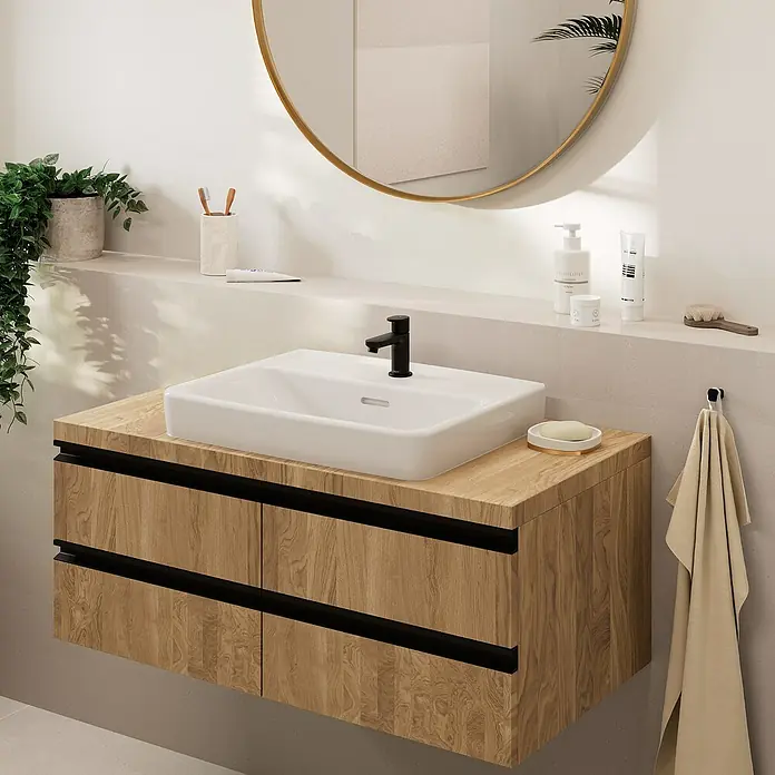Hansgrohe Vernis Blend Waschtischarmatur 70 - Schwarz, Matt - Modernes Badezimmerwaschbecken mit Holzunterschrank und Aufsatzwaschbecken, abgerundet durch einen goldenen Spiegel und stilvolle Accessoires.
