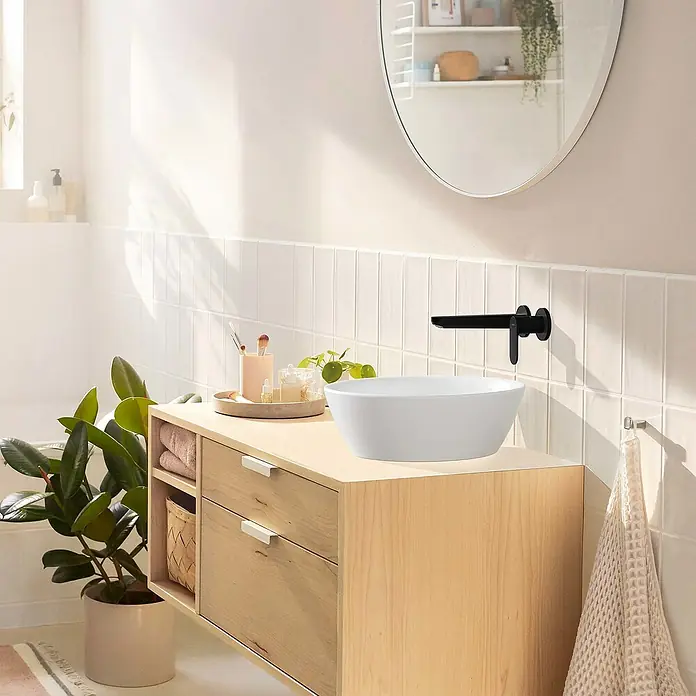 Hansgrohe Rebris S Waschtischarmatur 200 - Schwarz, Matt - Bild eines modernen Badezimmers mit einem weißen Aufsatzwaschbecken auf einem Holzunterschrank und einem schwarzen Wandarmatur.