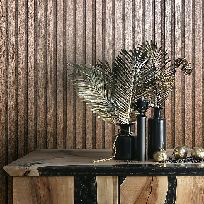 Marburg Travertino Vliestapete Paneel-Optik - Kupfer, Metalloptik, 10,05 x 0,53 m - Dekorative Komposition aus schwarzen Vasen und goldenen Akzenten auf einem Holzschrank vor einer strukturierten Wand.