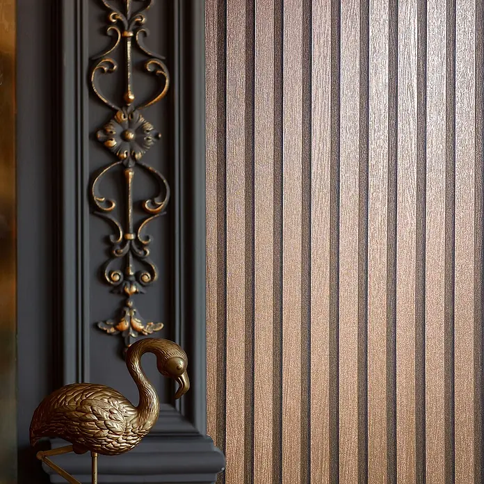 Marburg Travertino Vliestapete Paneel-Optik - Kupfer, Metalloptik, 10,05 x 0,53 m - Elegantes Interieur mit einer goldenen Flamingo-Skulptur, verziertem Paneel und einer stilvollen Wand mit vertikalen Streifen.