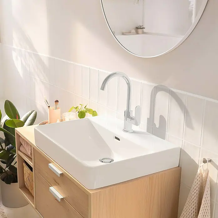 Hansgrohe Rebris S Waschtischarmatur 210 - Chrom, Glänzend - Modernes Badezimmerwaschbecken mit klaren Linien und Armatur, eingebaut in einen hellen Holzunterschrank mit Handtüchern und grüner Pflanze.