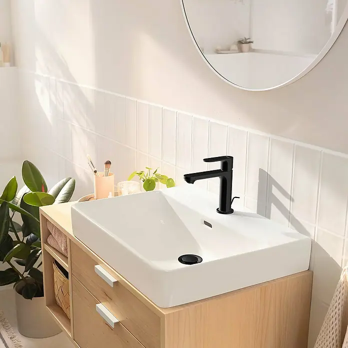 Hansgrohe Rebris S Waschtischarmatur 110 - Schwarz, Matt - Ein modernes Badezimmerwaschbecken mit einer eleganten schwarzen Armatur und einem Unterschrank aus hellem Holz. Die Waschbeckenarmatur ist ein echter Hingucker.