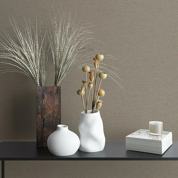Marburg Travertino Vliestapete Struktur - Braun, Steinoptik, 10,05 x 0,53 m - Das Arrangement zeigt dekorative Vasen, Federn, Trockenblumen, Bücher und eine Kerze auf einem stilvollen Regal.