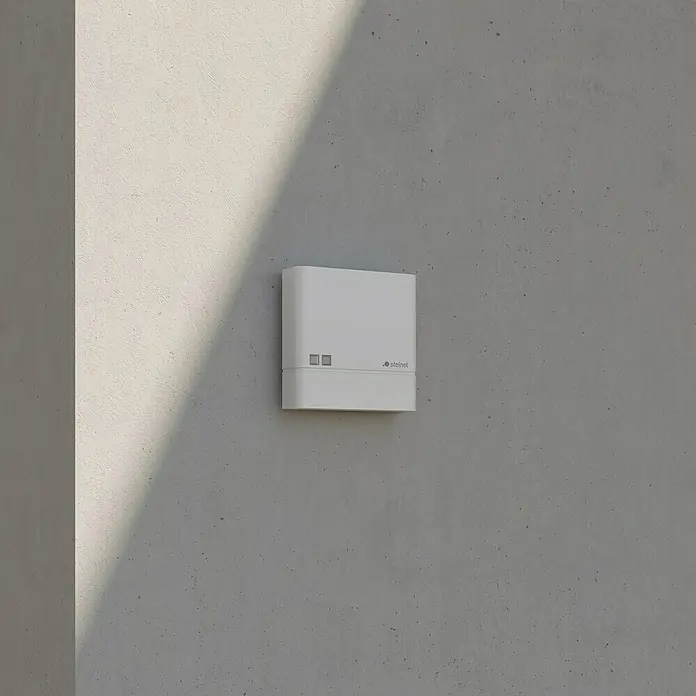 Steinel Dämmerungssensor NightmatIQ - Weiß - Nahaufnahme eines weißen Steinel-Bewegungsmelders an einer Betonwand, der modernes Design und Funktionalität vereint.