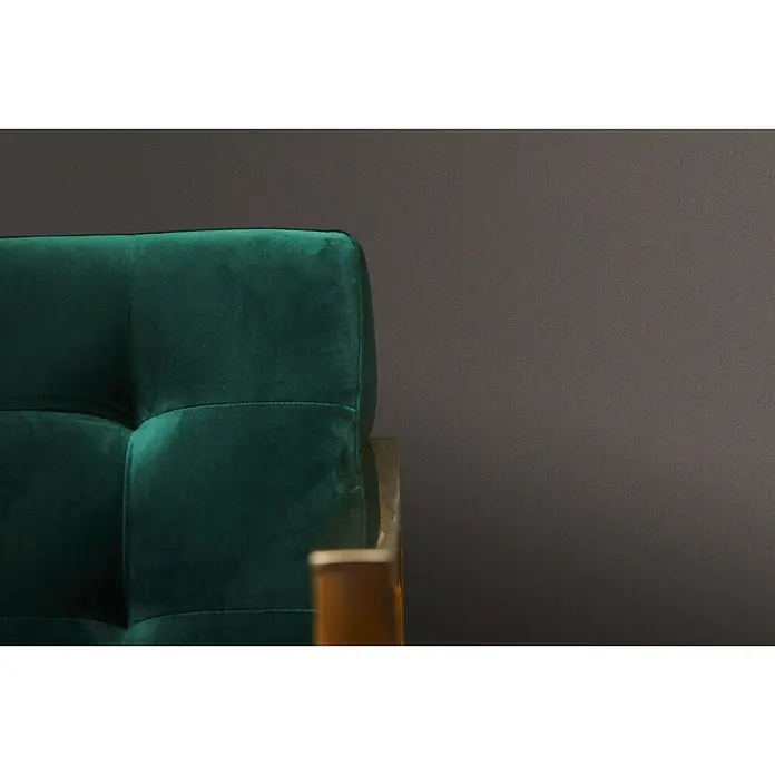 A.S. Création Metropolitan Stories Vliestapete Uni-Flat - Braun, Uni, 10,05 x 0,53 m - Nahaufnahme eines smaragdgrünen Samtsofas mit Knopfheftung und Holzrahmen vor einem dunklen Hintergrund.