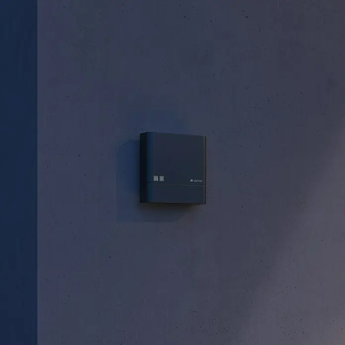 Steinel Dämmerungssensor NightmatIQ Plus - Anthrazit - Nahaufnahme einer grauen Steinel-Außenleuchte an einer grauen Wand. Die Leuchte ist kompakt und modern gestaltet und sorgt für eine angenehme Beleuchtung.