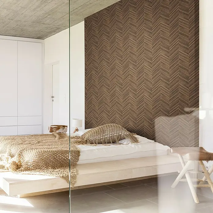 Marburg Travertino Vliestapete Fischgrätmuster - Dunkelbraun, Holzoptik, 10,05 x 0,53 m - Schlafzimmer mit schlichtem, niedrigem Bett, strukturiertem Wandpaneel und minimalistischem Design, das natürliche und moderne Elemente vereint.