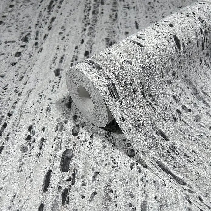 Marburg Travertino Vliestapete Struktur - Hellgrau-Grau, Steinoptik, 10,05 x 0,53 m - Graue Tapetenrolle mit einem faszinierenden Muster aus dunklen Flecken und einer körnigen Textur, perfekt für moderne Innenräume.
