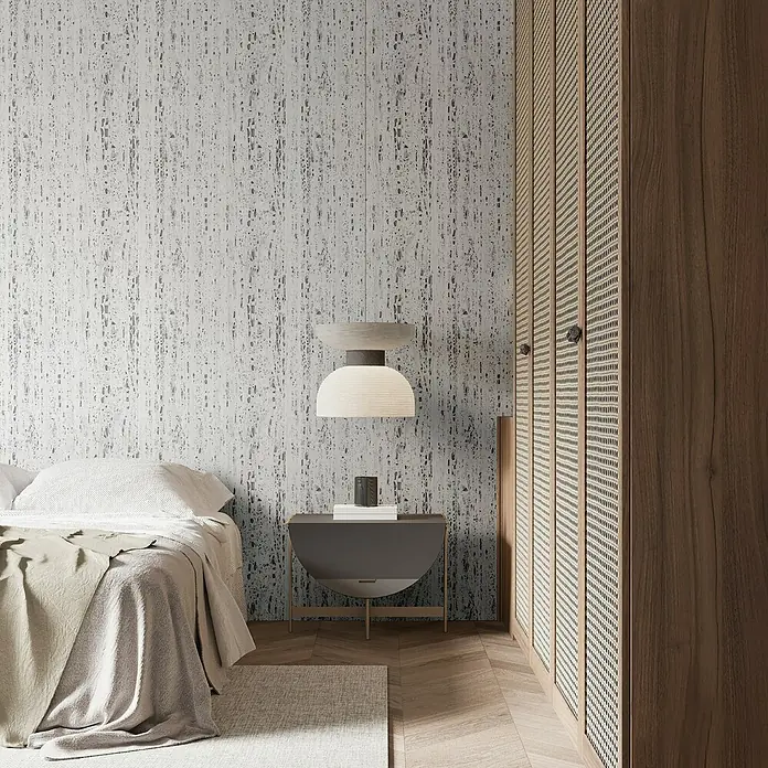 Marburg Travertino Vliestapete Struktur - Weiß-Grau, Steinoptik, 10,05 x 0,53 m - Schlafzimmer mit Bett, Nachttischlampe und einem Schrank mit Rattangeflecht. Das Zimmer ist mit einer stilvollen Tapete dekoriert.