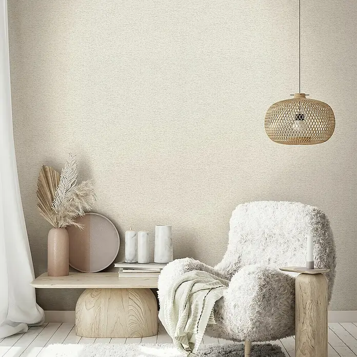 Marburg Travertino Vliestapete Struktur - Beige, Steinoptik, 10,05 x 0,53 m - Ein gemütlicher Sessel mit flauschigem Bezug, ergänzt durch eine dekorative Lampe und Beistelltische, schafft eine entspannende Raumatmosphäre.