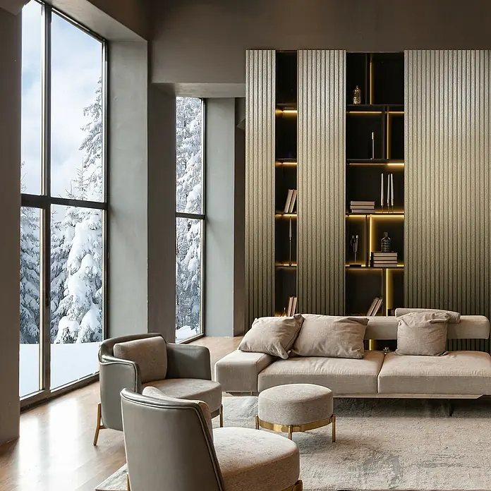 Marburg Travertino Vliestapete Paneel-Optik - Gold, Metalloptik, 10,05 x 0,53 m - Gemütliches Wohnzimmer mit beigem Sofa, Sesseln und Bücherregal. Einladendes Interieur mit Blick auf eine verschneite Winterlandschaft.