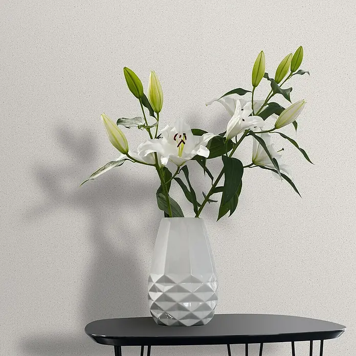 Marburg Travertino Vliestapete - Weiß, Uni, 10,05 x 0,53 m - Elegante weiße Lilien in einer modernen weißen Vase auf einem dunklen Tisch vor einem hellen Hintergrund.