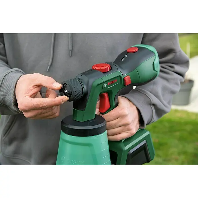 Bosch Power for All 18V Akku-Farbsprühsystem AdvancedSpray 18V-500 - 18 V, 1 Akku, 4 Ah, Max. Fördermenge: 0,5 l/min - Eine Bosch Farbspritzpistole AdvancedSpray 18V-500 wird von einer Person gehalten, die die Düse mit den Fingern justiert.