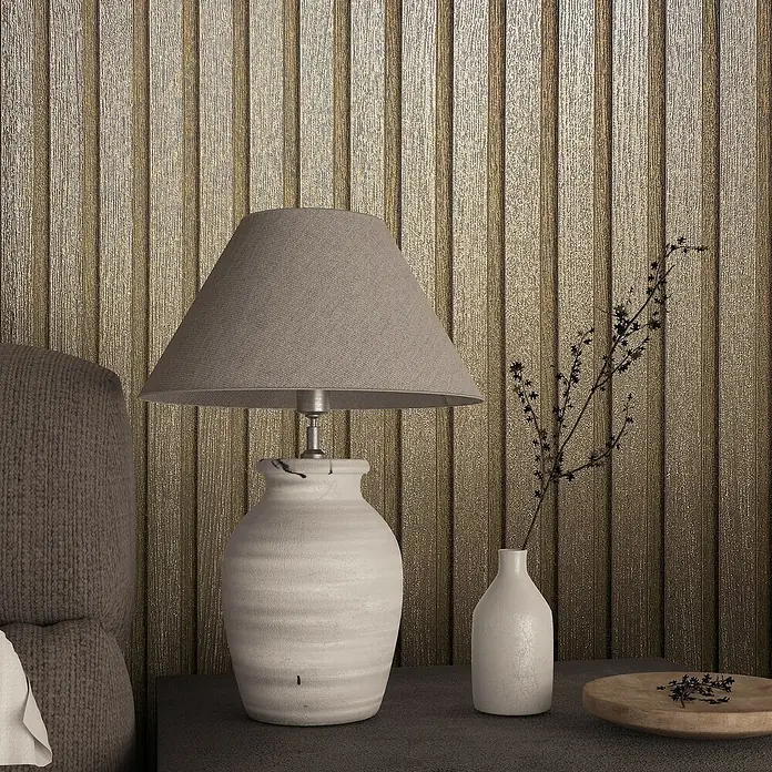 Marburg Travertino Vliestapete Paneel-Optik - Gold, Metalloptik, 10,05 x 0,53 m - Nahaufnahme einer rustikalen Tischlampe mit beigem Schirm, auf einem Tisch neben einer kleinen Vase und einer Holzschale.