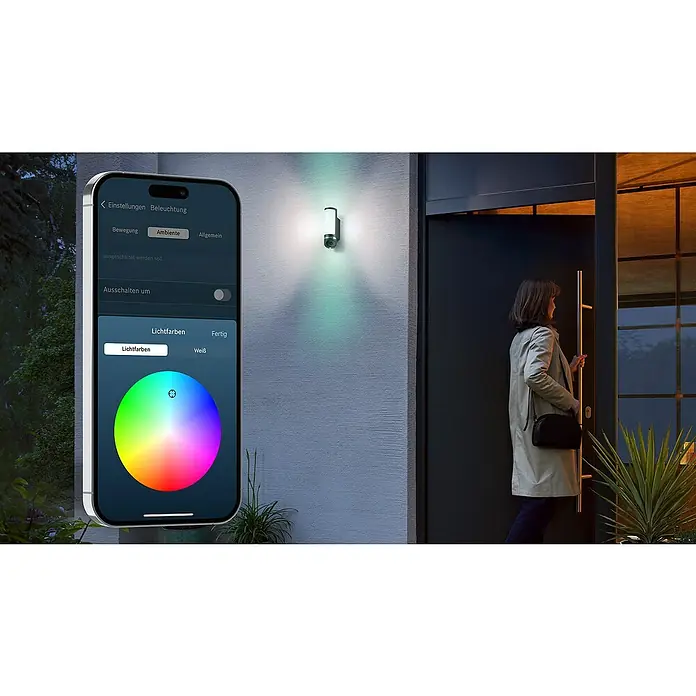 Bosch Smart Home Außenkamera Eyes II - 1.080 Pixel (Full HD), Silber, Erfassungswinkel: 180 °, Erfassungsreichweite: 8 m - Intelligente Außenleuchte mit Farbanpassung per Smartphone-App, während eine Frau das Haus betritt.