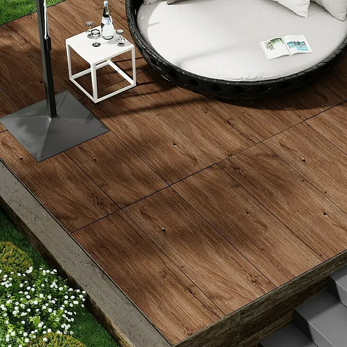 Marazzi Terrassenfliese Esterno 20T Woodliving Scuro - 40 x 120 x 2 cm, Braun, Matt - Einladende Terrasse mit Holzdielen, Sonnenschirm, Beistelltisch und gemütlichem Lounge-Bett. Entspannung im Freien.
