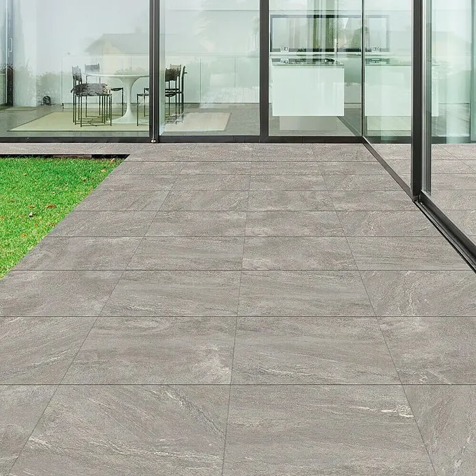 Diephaus Terrassenfliese Columbia - 60 x 60 x 4 cm, Quarzit, Beton - Graue Steinzeugfliesen erstrecken sich von der Terrasse bis zum Haus und schaffen einen nahtlosen Übergang zwischen Innen- und Außenbereich.